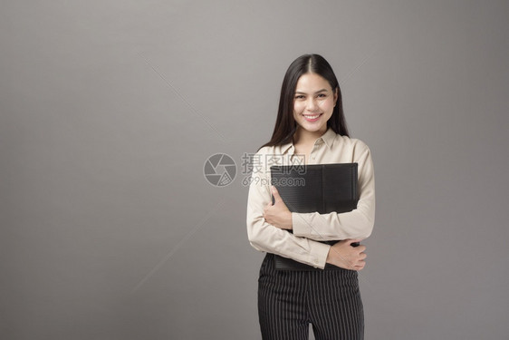 美丽的商业女人肖像灰色背景的笑容图片