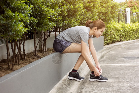 美丽的女人正系着她鞋子图片