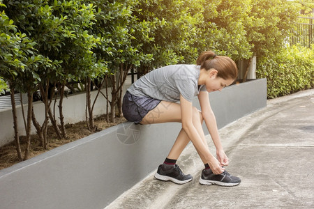 美丽的女人正系着她鞋子图片