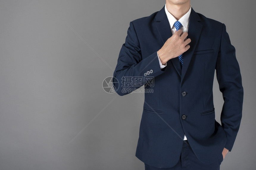 身穿蓝西装的商人以灰色背景充满信心图片