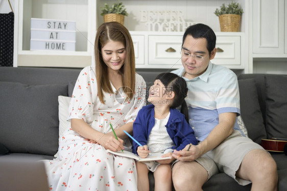 快乐的亚洲父母教可爱的小女儿做功课在家里一起画图片