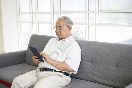 一个快乐的亚洲老人在家里用平板电脑和家人通过网络摄像头聊天退休的概念图片