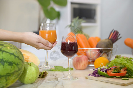 紧握着一杯健康果汁的手厨房桌上蔬菜和果汁健康概念图片