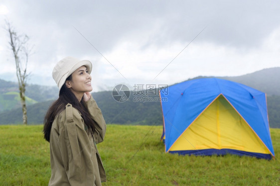 一位快乐的旅游妇女享受和放松在难民营帐篷附近在美丽的绿色山上在雨季热带气候图片