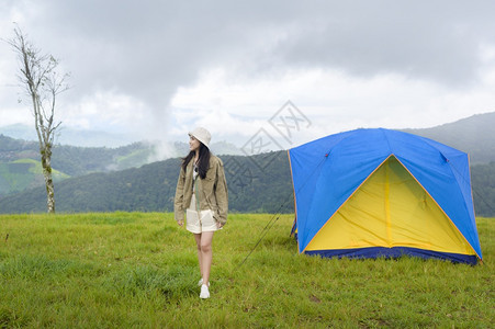 一位快乐的旅游妇女享受和放松在难民营帐篷附近在美丽的绿色山上在雨季热带气候图片