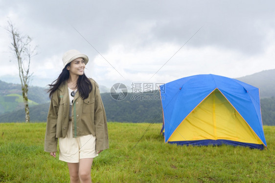 一位快乐的旅游妇女享受和放松在难民营帐篷附近在美丽的绿色山上在雨季热带气候图片