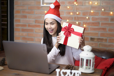手绘圣诞老人一位戴着红色圣诞老人帽子的微笑年轻女在圣诞节当天与家人和朋友在社交网络上进行视频通话背景