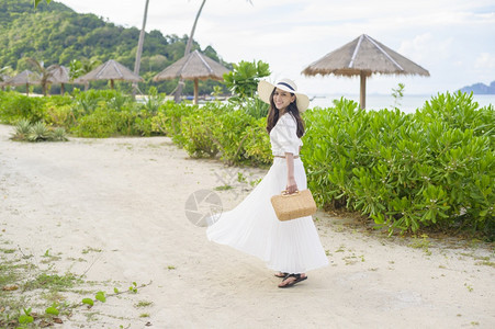 一个穿着白裙子的快乐美丽女人在海滩夏天和节假日享受放松图片