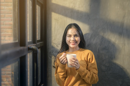 阳光照耀的年轻美女在家享受早晨的咖啡图片