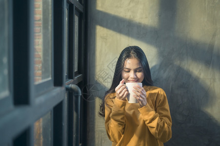 阳光照耀的年轻美女在家享受早晨的咖啡图片