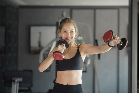 年轻女孩在健身房用哑铃运动锻炼图片