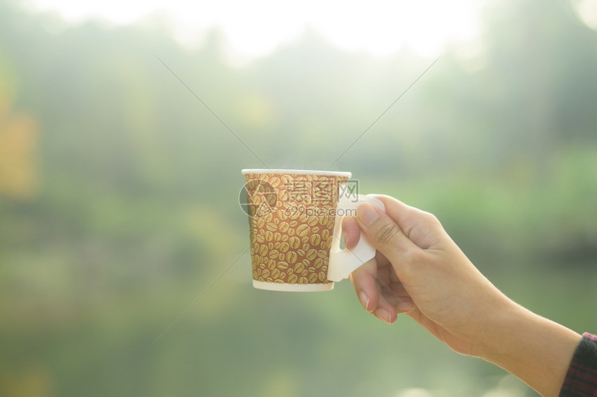 近距离观察人类早晨在大自然背景上拿着热咖啡图片
