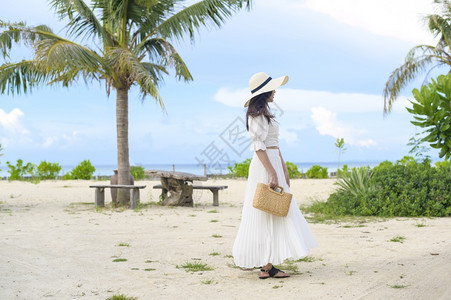 一个穿着白裙子的快乐美丽女人在海滩夏天和节假日享受放松图片