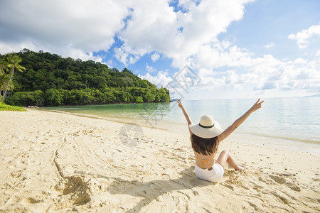 一个快乐的美丽女人在黄色比基尼享受和放松在海滩夏天和节假日的概念图片