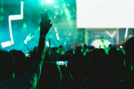 音乐会人群节在舞台灯上使用移动智能手机图片