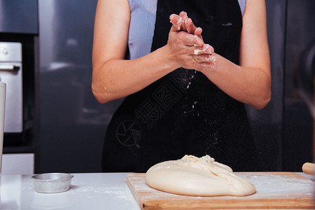女面包师手在餐桌上做面粉团图片