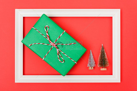 新年圣诞节组成绿色fir树枝和绿色礼品盒的顶端视图以红背景和复制空间为框架图片