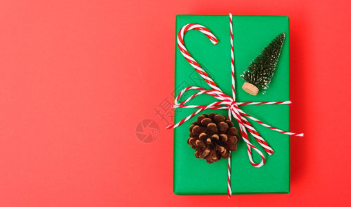 新年圣诞节的构成顶视礼物绿箱绳子的割缝和红背景绿色fir树枝以及复制空间图片