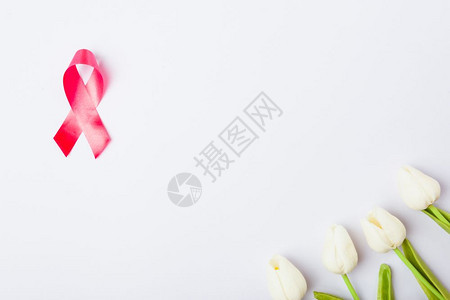 乳癌月概念平面顶楼粉红丝带和白背景的郁金香花并附上文本的复制空间图片