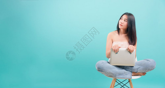 坐在椅子上的亚洲快乐肖像美丽的年轻女士坐在椅子上微笑着她拿笔记本电脑图片