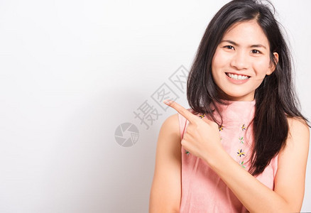 站在白牙面前微笑着的亚洲美丽年轻女她举起手指看摄影机用白色背景在工作室拍摄照片图片