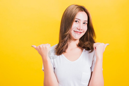 穿着白色T恤站在成功女子面前在摄影棚拍时举起两个拇指手势标志在黄色背景和复制空间上被孤立图片