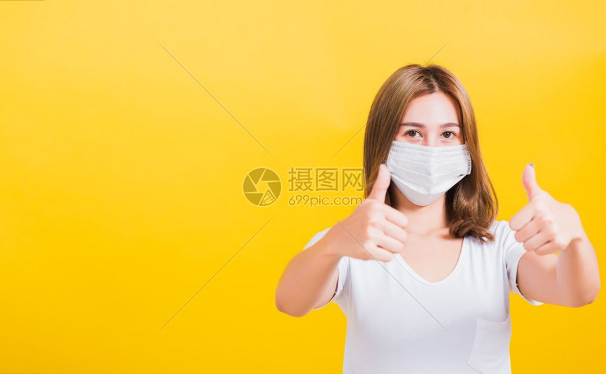 身戴面具保护的泰国美丽年轻快乐女展示拇指好阻止爆发控制保健护理图片