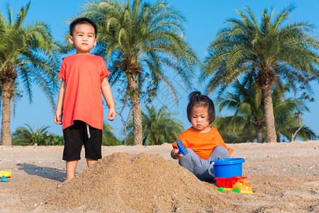 亚裔泰国人快乐可爱的小快乐弟和妹两个孩子的和两个孩子在夏日用复制空间在户外热带海滩用沙子挖玩耍具图片
