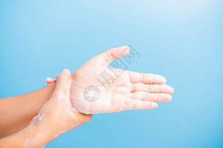亚洲青年妇女用肥皂洗手时有泡沫卫生预防COVID19或冠状保护概念蓝底隔离图片
