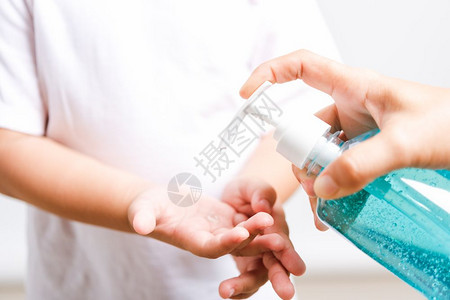 使用瓶装泵喷水器净化剂酒精凝胶清洗手的小孩子男COVID19或冠状保护概念带复制空间的孤立白背景图片