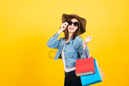亚洲快乐的肖像美丽可爱的年轻少女带着太阳镜微笑的年轻少女站在太阳镜面前兴奋地拿着购物袋图片