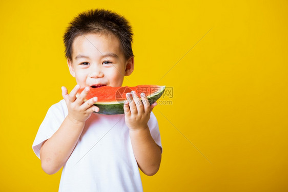 快乐的亚洲儿童或孩子可爱的小男孩笑玩着切开西瓜新鲜食物拍片室摄孤立在黄色背景上健康食物和夏季概念图片