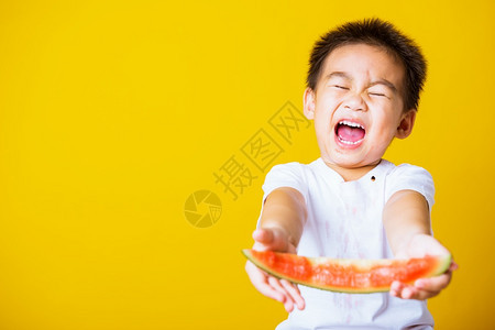 快乐的亚洲儿童或孩子可爱的小男孩笑玩着切开西瓜新鲜食物拍片室摄孤立在黄色背景上健康食物和夏季概念图片