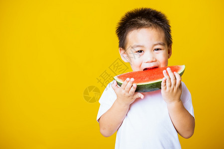 快乐的亚洲儿童或孩子可爱的小男孩笑玩着切开西瓜新鲜食物拍片室摄孤立在黄色背景上健康食物和夏季概念图片