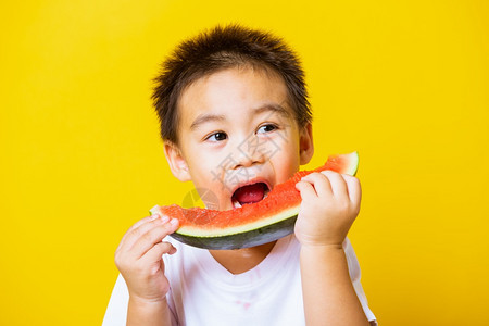 快乐的亚洲儿童或孩子可爱的小男孩笑玩着切开西瓜新鲜食物拍片室摄孤立在黄色背景上健康食物和夏季概念图片