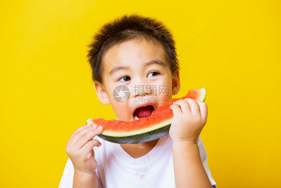 快乐的亚洲儿童或孩子可爱的小男孩笑玩着切开西瓜新鲜食物拍片室摄孤立在黄色背景上健康食物和夏季概念图片