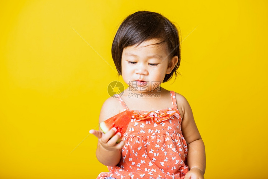 快乐的亚洲小宝或可爱女孩快乐的肖像有吸引力的笑穿着T恤衫的笑玩T恤衫拿着切开的西瓜新鲜图片