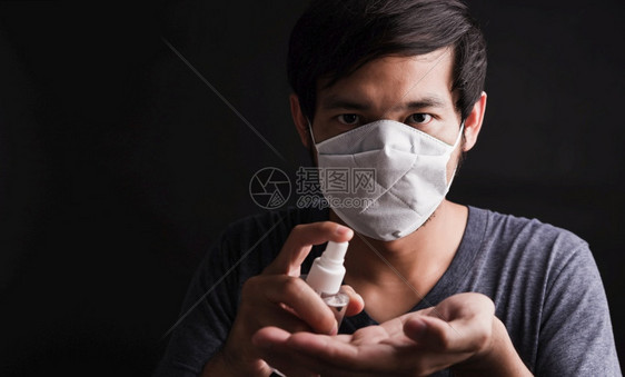 身戴保护面罩的亚洲帅男子在眼部握住恐惧的面具时穿着保护面罩的遮脸帅男子展示了近脸喷洒防毒剂卫生预COVID19或黑底暗的冠状保护图片