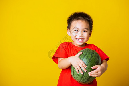 快乐的亚洲儿童或孩子可爱的小男孩带着红色T恤的笑脸穿着红色T恤的笑脸玩着全西瓜图片