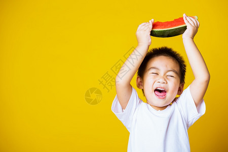 快乐的亚洲儿童或孩子可爱的小男孩笑玩着切开西瓜新鲜食物拍片室摄孤立在黄色背景上健康食物和夏季概念图片