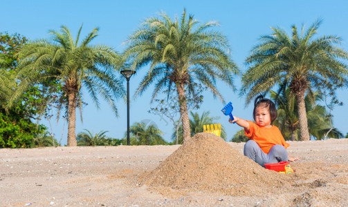 亚裔泰国快乐可爱的小快乐女儿孩在夏季日与影印空间在户外热带海滩用沙子挖玩的具图片