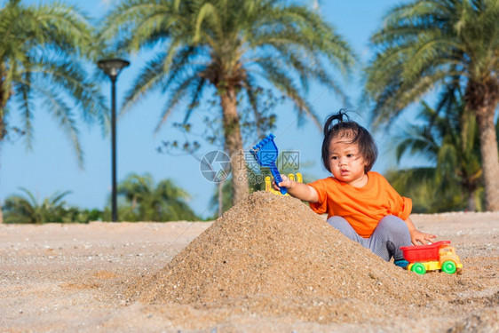 亚裔泰国快乐可爱的小快乐女儿孩在夏季日与影印空间在户外热带海滩用沙子挖玩的具图片
