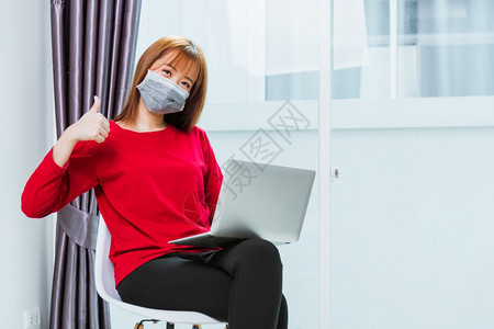 亚洲年轻商业女青用笔记本电脑在家庭办公室工作坐在椅子上戴面罩保护用笔记本电脑隔离冠状或COVID19图片