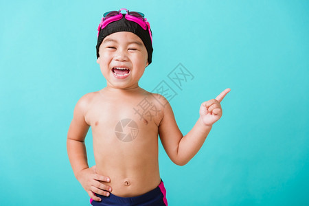 暑假概念近身肖像亚洲快乐可爱的小男孩穿着护目镜和泳衣小孩在暑假点玩得开心摄影棚拍孤立的蓝背景图片