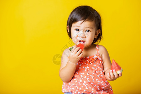 快乐的亚洲小宝或可爱女孩快乐的肖像有吸引力的笑穿着T恤衫的笑玩T恤衫拿着切开的西瓜新鲜图片