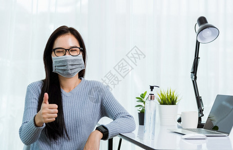 身戴面罩的亚洲年轻商业美女身穿面罩在家办公室工作用笔记本电脑柜台隔离疾病冠状毒图片