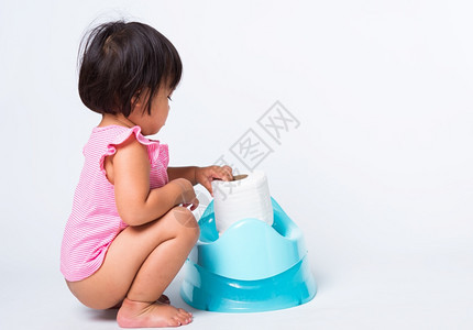 亚洲可爱的小婴儿女教育培训练他们坐在蓝室锅或便壶上手持卫生纸卷在白色背景上孤立的演播室拍摄Wc厕所概念图片