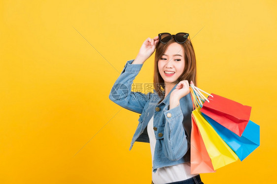 亚洲快乐肖像美丽可爱的年轻女子微笑着的年轻少女站在太阳镜边兴奋地拿着购物袋图片
