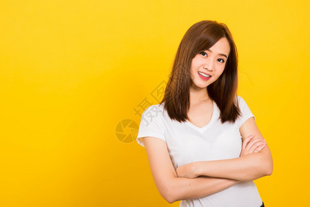亚洲快乐肖像美丽的可爱年轻女孩站着穿T恤衫微笑满的双臂看着镜头被孤立图片
