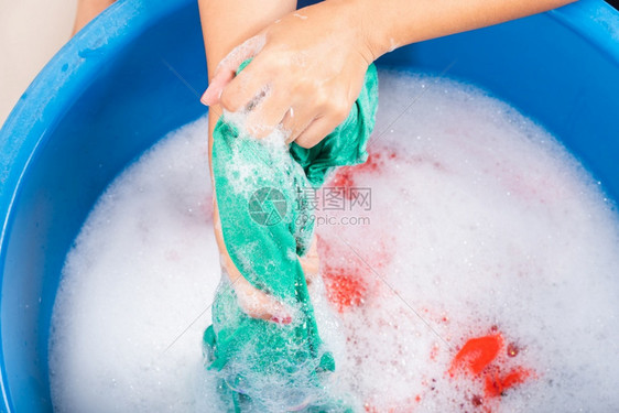 近身的亚洲年轻女子在盆地用手洗彩色衣服带涤剂有肥皂泡水工作室拍摄背景洗衣服概念图片